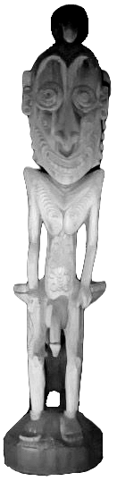 black and white image of a wooden sculpture of a man, grinning mischeviously, standing nude on a pedestal, head disproportionately large to body and skinny limbs
